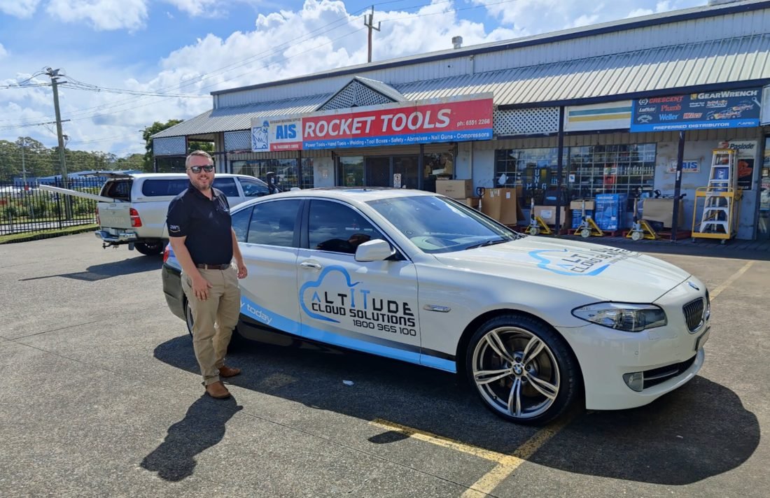 ACS director beside a branded Altitude Cloud Solutions car